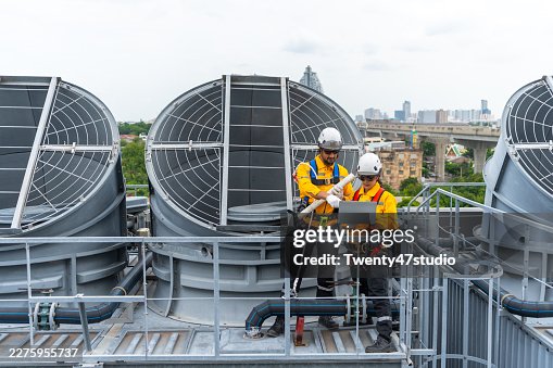 Construction workers using safety harnesses while performing a routine chiller inspection on a high-rise building Construction workers using safety harnesses while performing a routine chiller inspection on a high-rise building