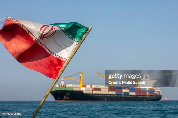 An Iranian flag flutters in the wind as ships remain anchored on May 16, 2026 in the Strait of Hormuz near Larak Island, Iran. Negotiations between...