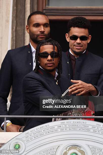Bayern Munich's French midfielder Michael Olise holds the trophy as Bayern Munich's players celebrate their 35th Bundesliga championship title at the...