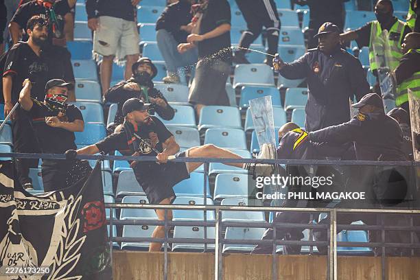 Supporters clash with South African Police Service officers in the stands during the CAF Champions League final first leg football match between...