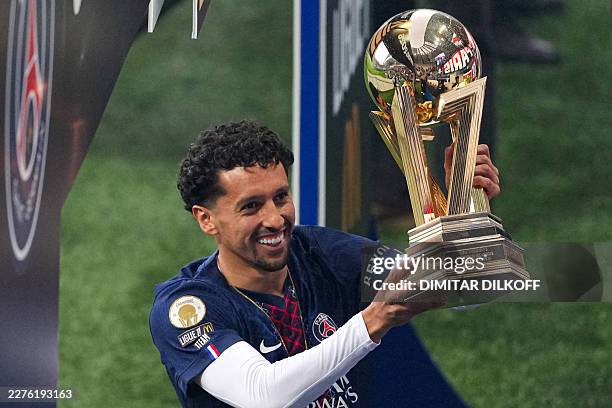 Paris Saint-Germain's Brazilian defender Marquinhos holds the French Ligue 1 trophy to celebrate with teammates after winning the championship, ahead...