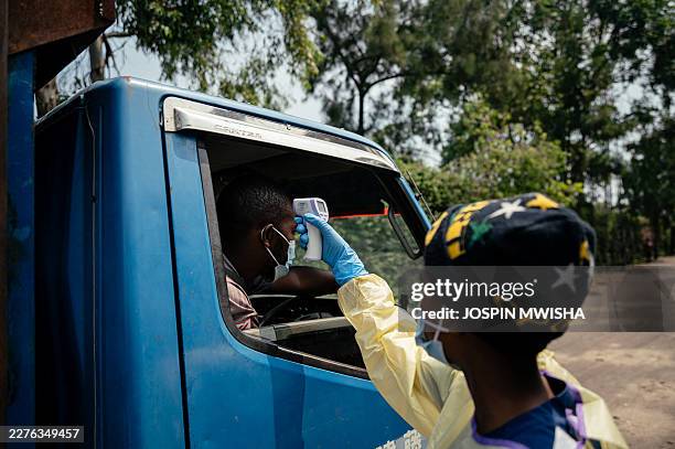 Visitor has their temperature checked by a health worker using a thermoflash before entering Kyeshero Hospital at a checkpoint for temperature...