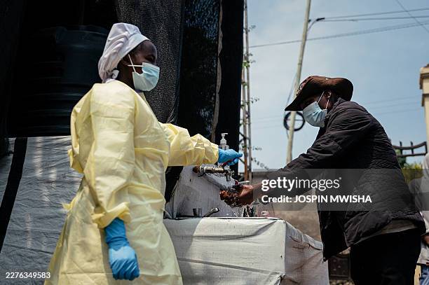Visitor washes his hands before entering Kyeshero Hospital at a checkpoint for hand washing and temperature screening for all visitors and patients...