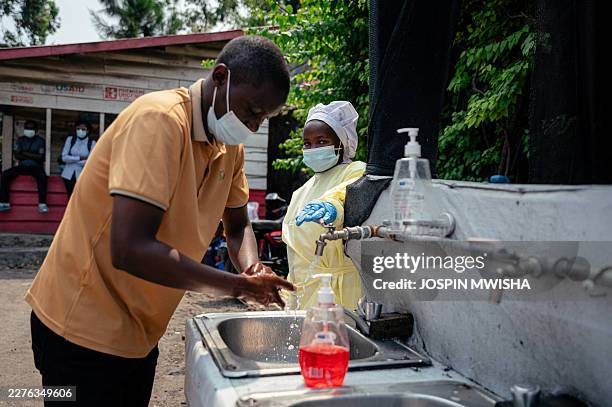 Visitor washes his hands before entering Kyeshero Hospital at a checkpoint for hand washing and temperature screening for all visitors and patients...
