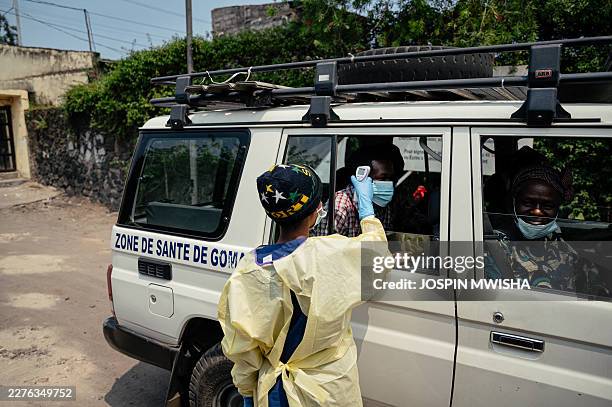 Visitor has their temperature checked by a health worker using a thermoflash before entering Kyeshero Hospital at a checkpoint for temperature...