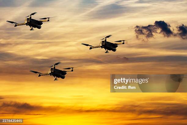 three drones flying in formation against dramatic sunset sky - veículo aéreo de combate não tripulado - fotografias e filmes do acervo
