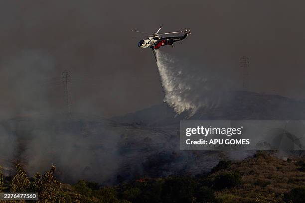 Fire Department helicopter drops water on the Sandy Fire as it burns in the hills near a residential area in Simi Valley, California on May 18, 2026....