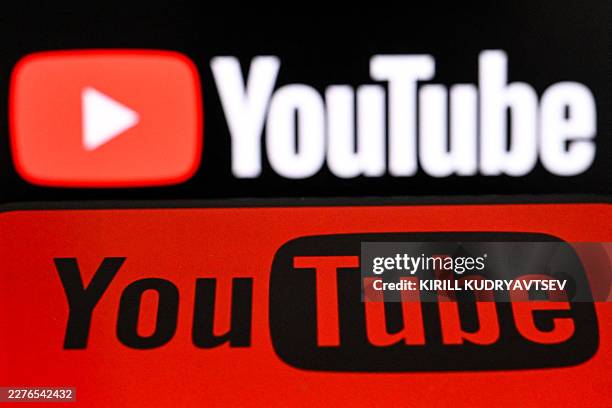 Photo taken on May 19, 2026 shows the US video platform Youtube displayed on a smartphone in front of the Youtube's logo on a laptop screen in...