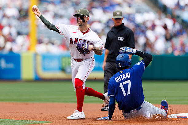 Zach Neto of the Los Angeles Angels throws as Shohei Ohtani of the Los Angeles Dodgers slides into second base during the game at Angel Stadium of...