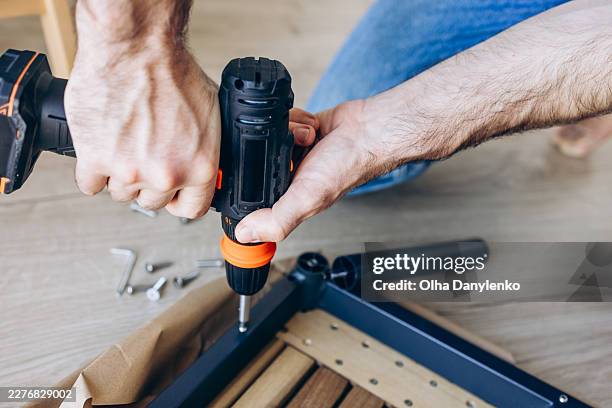 close-up of handyman using power drill to assemble furniture. diy home improvement, self assembly, repair work, and modern living concept. - broca imagens e fotografias de stock