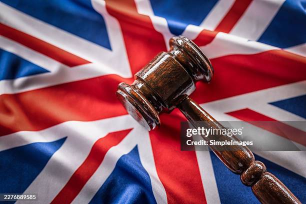 a close-up of a wooden judge's gavel resting on a union jack. this composition symbolically represents the british legal system, the judiciary, or legislative decisions in the united kingdom. - legislation stock pictures, royalty-free photos & images
