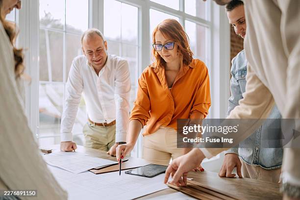 team of architects discussing project plans while inspecting design materials indoors - project management stock pictures, royalty-free photos & images