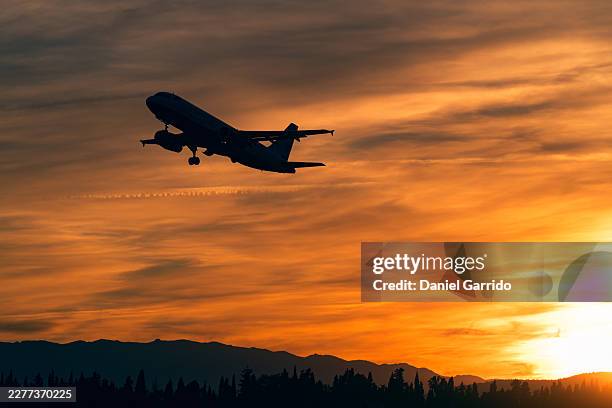 commercial airplane taking off in silhouette against sunset sky over mountains. - wonderlust imagens e fotografias de stock