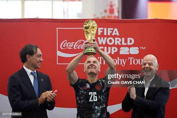 Canada's Prime Minister Mark Carney hoists up the FIFA World Cup Trophy, as FIFA President Giovanni Infantino and Italian football coach...