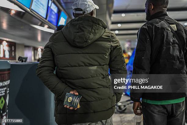 Ghanaian national holds his passport while standing at the check-in desk for an evacuation flight at OR Tambo International Airport in Ekurhuleni on...