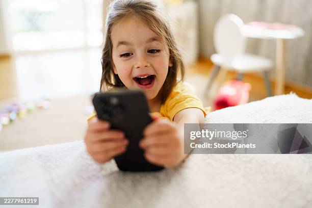 happy child watching exciting content on smartphone at home - endast en flicka bildbanksfoton och bilder