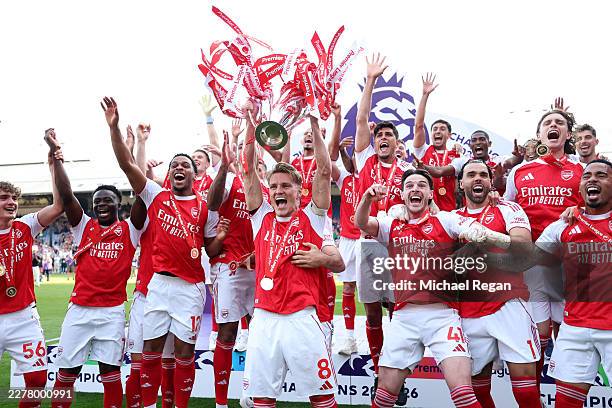 Martin Odegaard of Arsenal lifts the Premier League trophy as players of Arsenal celebrate, as they are crowned the Champions of the Premier League...
