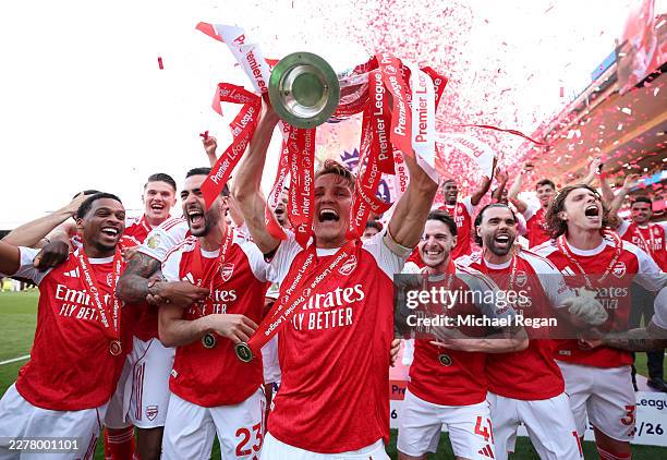Martin Odegaard of Arsenal lifts the Premier League trophy as players of Arsenal celebrate, as they are crowned the Champions of the Premier League...