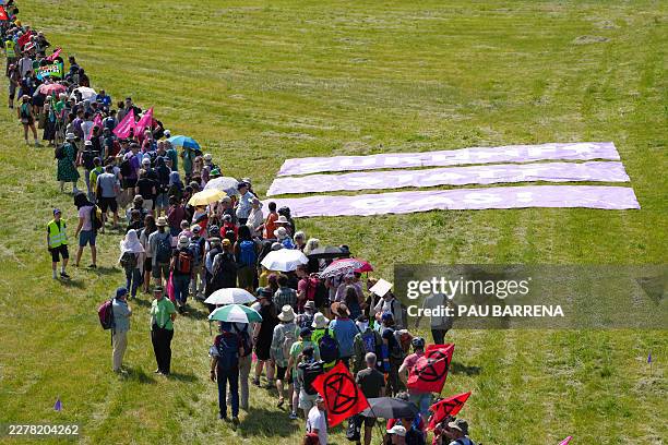 Demonstrators queue to form a large human wind turbine next to a placard reading 'Future instead gas' as they take part in a demonstration under the...