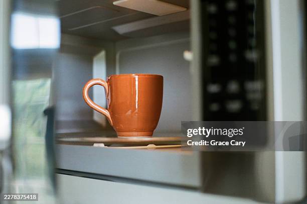 orange mug in microwave - microwave stock pictures, royalty-free photos & images
