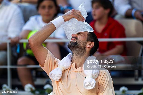 Novak Djokovic of Serbia shows the agony of the heat as he cools off between games late in the fourth set on a stiflingly hot day during his match...