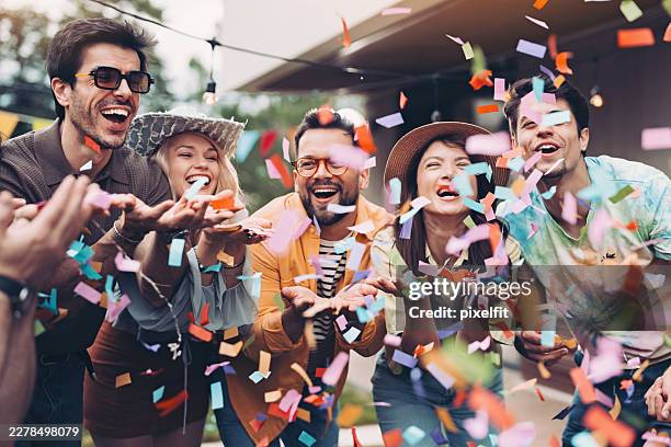 group of friends blowing confetti on a party - tuinfeest stockfoto's en -beelden