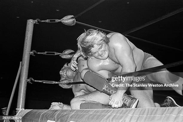 American professional wrestler Ric Flair tangled in the corner ropes has his leg held by American professional wrestler Greg Valentine during a...