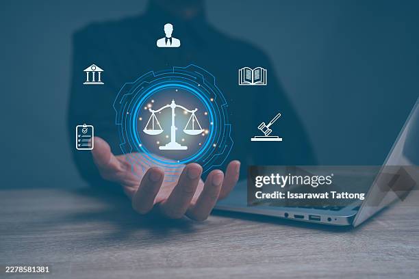 businessman or lawyer holding balance of justice while using computer application for legal study, regulation, compliance, and corporate law concepts, - gesetzgebung stock-fotos und bilder