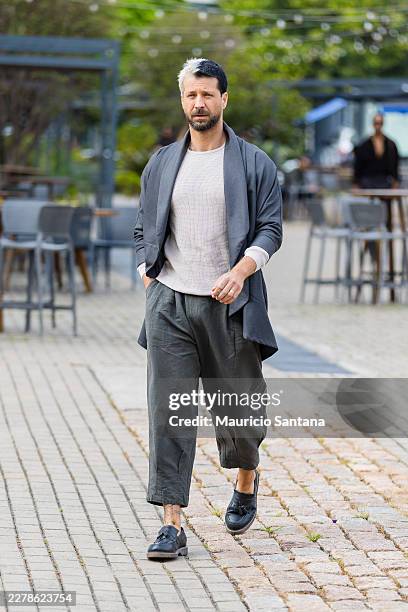 Guest wears short bleached and dark hair, layered style, white crew neck t-shirt, textured fabric, charcoal oversized blazer, draped silhouette,...