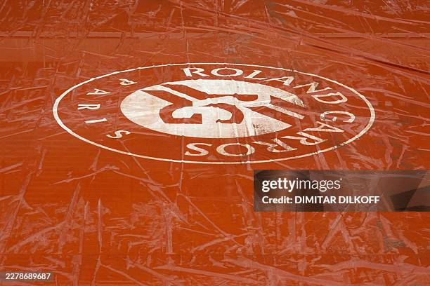 This photograph shows the Roland-Garros logo of a wet tarpaulin covering a court after heavy rain on day 10 of the French Open tennis tournament at...