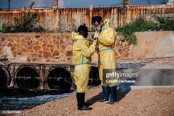 workers adjusting full face gas masks in toxic zone - protective suit stock pictures, royalty-free photos & images