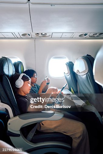 Niños viajando en avión usando dispositivos digitales para el entretenimiento Niños viajando en avión usando dispositivos digitales para el entretenimiento