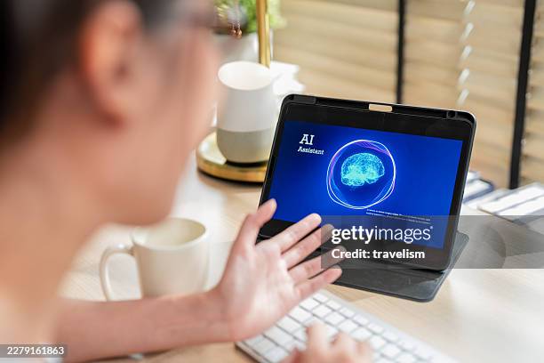 cheerful asian woman typing on keyboard and interacting with ai brain interface on tablet at home desk for future of work machine learning software smart automation digital workspace - hybrid cloud computing stock pictures, royalty-free photos & images