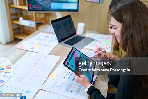 Ux designer creating user interface wireframes and mobile application prototypes on a digital tablet with a stylus, collaborating with a colleague in a modern office Ux designer creating user interface wireframes and mobile application prototypes on a digital tablet with a stylus, collaborating with a colleague in a modern office