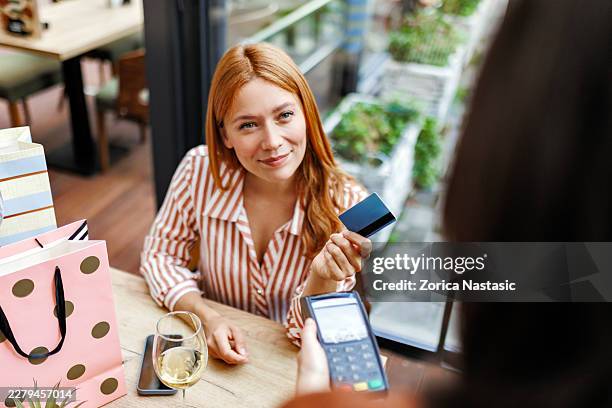 smiling young woman paying with credit card at coffee shop - cash register stock pictures, royalty-free photos & images