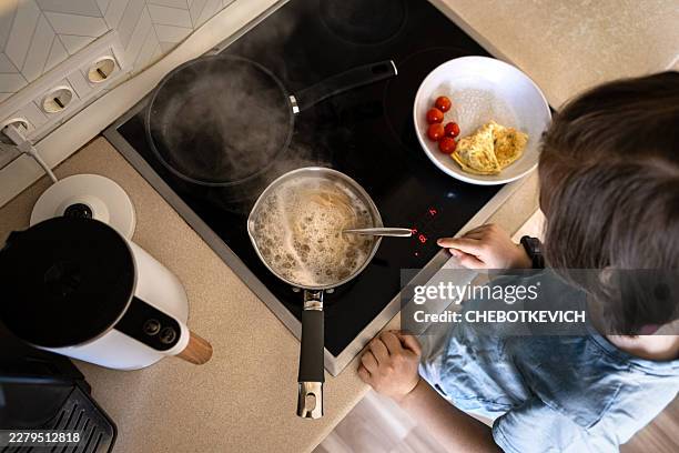 vista en ángulo alto de un niño cocinando en una cocina eléctrica - hervir fotografías e imágenes de stock