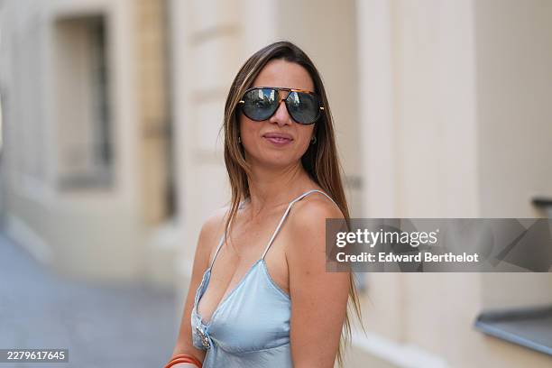 Maria Rosaria Rizzo wears long straight brown hair with lighter ends and a center part, black aviator sunglasses with dark lenses and gold-tone...
