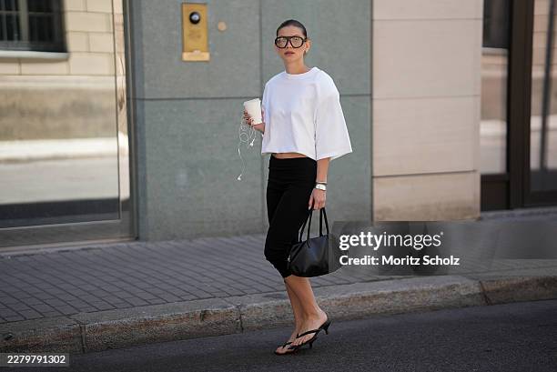 Sophia Geiss is seen wearing a white oversized T-shirt by The Frankie Shop; black cropped capri leggings by Mango; black kitten-heel flip-flop...