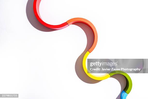 colorful wooden rainbow blocks forming a curved wave path - sequenzielle abfolge stock-fotos und bilder