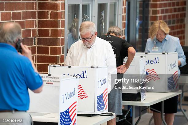 People fill out ballots as a poll worker makes a phone call on Election Day for the midterm primary on June 9, 2026 at Dreher High School in...