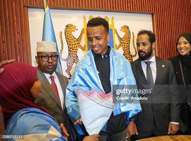 Somali referee Omar Abdulkadir Artan, draped in the Somali flag, receives flowers during a welcome ceremony following his arrival in Mogadishu,...
