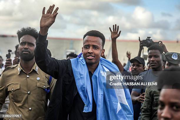 Somali international referee Omar Abdulkadir Artan waves to supporters while draped in the Somali flag as he is welcomed ahead of a solidarity...