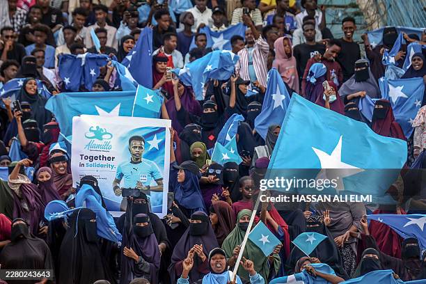 Supporters of Somali international referee Omar Abdulkadir Artan hold flags and banners as they welcome him ahead of a solidarity football match...