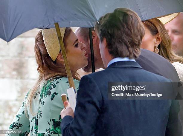 Princess Beatrice kisses cousin Prince William, Prince of Wales as they attend the wedding of Peter Phillips and Harriet Sperling at All Saints'...