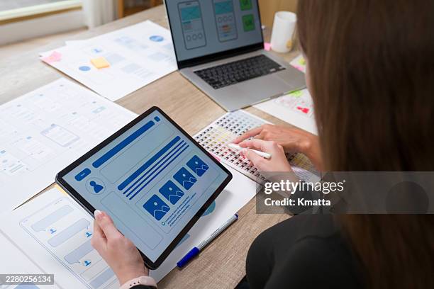 ux designer creating user interface wireframes and mobile application prototypes on a digital tablet with a stylus, collaborating with a colleague in a modern office. - graphic design layout stock pictures, royalty-free photos & images