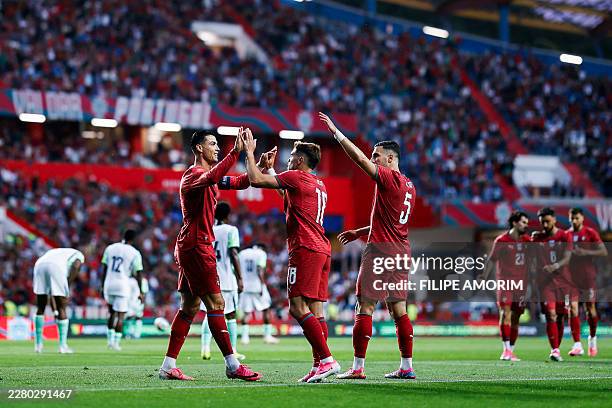 Portugal's midfielder Pedro Neto celebrates scoring the opening goal with Portugal's forward Cristiano Ronaldo during the international friendly...