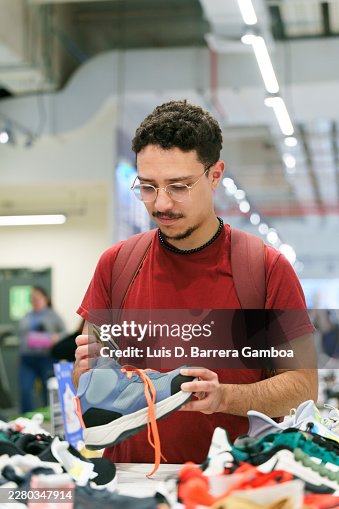 Latino man reading a sneaker tag while shopping in a retail store Latino man reading a sneaker tag while shopping in a retail store