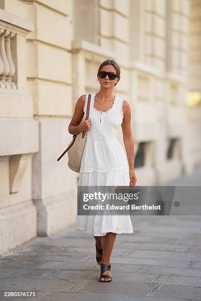 Diane Batoukina wears brown hair with a center part pulled back into a low bun, black rectangular aviator sunglasses with dark lenses by Kaleos, an...