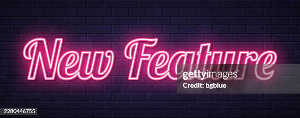 neues feature – leuchtender neontext auf backsteinwand-hintergrund - gebäudeteil stock-grafiken, -clipart, -cartoons und -symbole