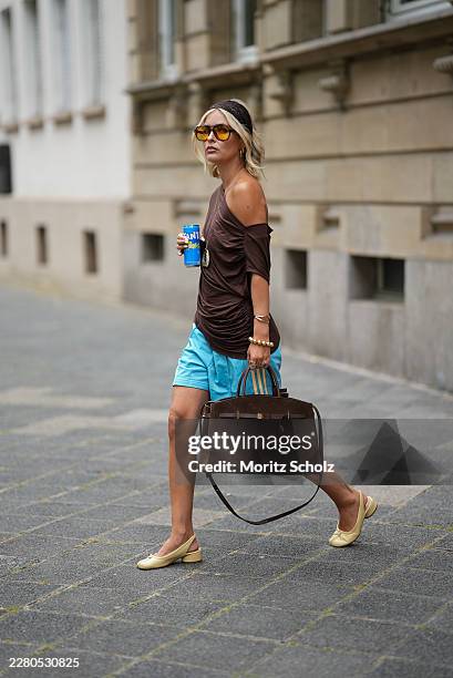 Julia Kammerer is seen wearing a dark brown draped jersey top with an off shoulder neckline and gathered side detailing from NA KD; light blue...